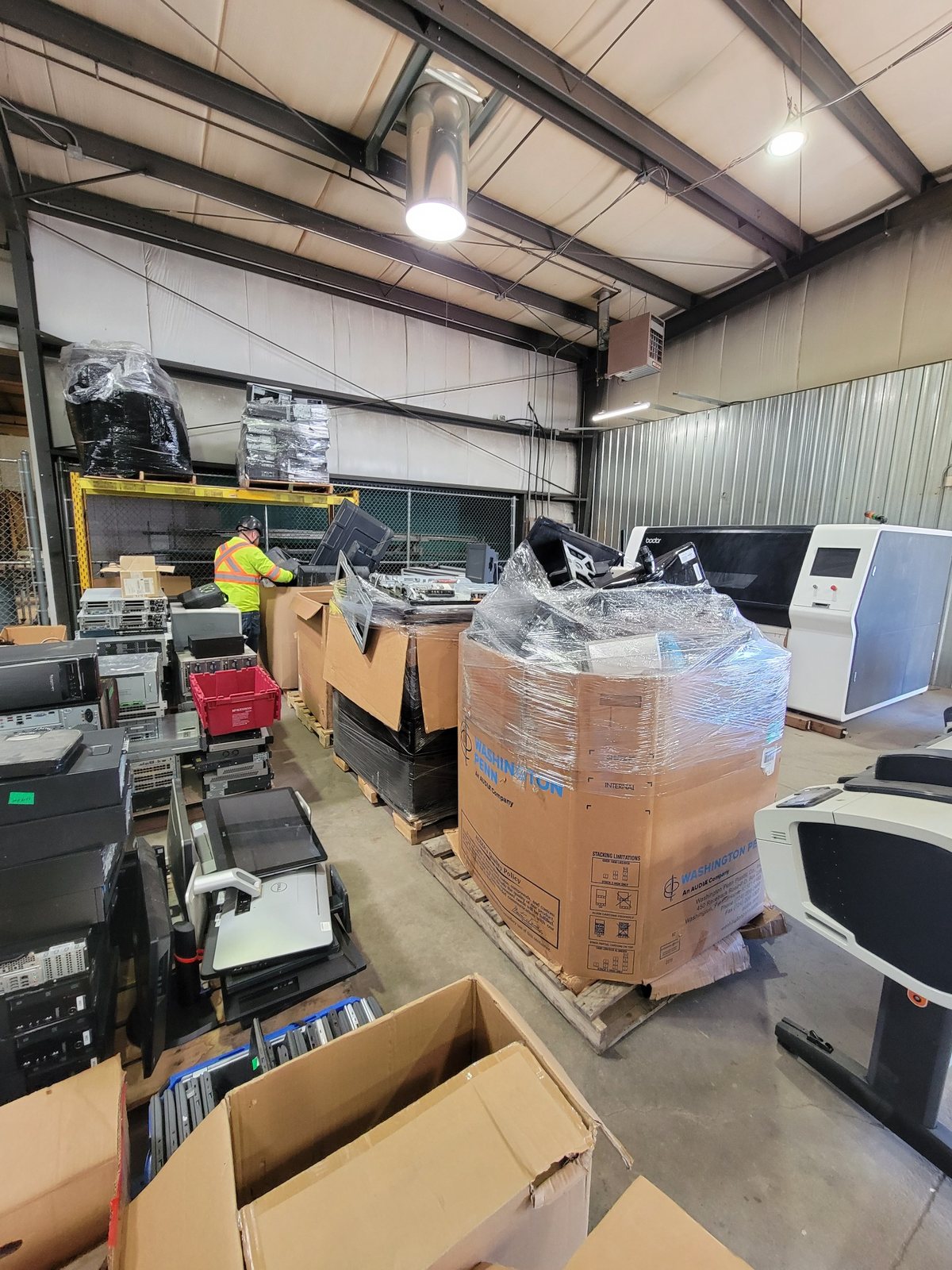 CPER warehouse worker sorting pallets of computers and electronic equipment for reuse and recycling